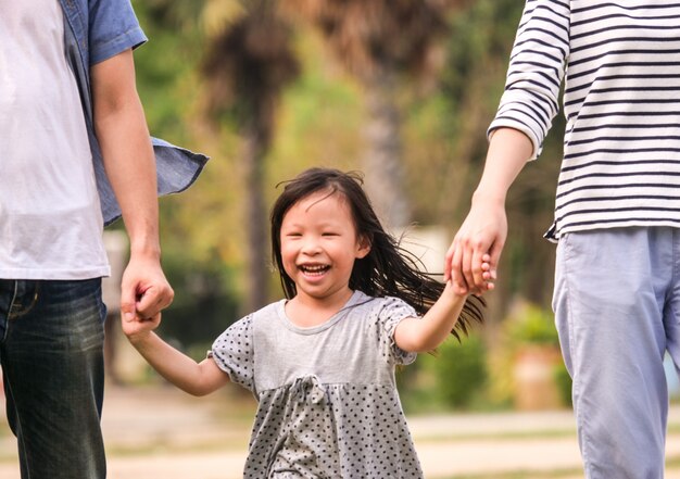 Zakończenie up szczęśliwa małej dziewczynki twarz trzyma ona rodzice wręcza runnung w parku, Szczęśliwy rodzinny pojęcie.