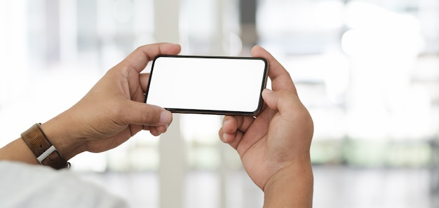Zakończenie widok biznesmen używa jego pustego ekranu smartphone z zamazanym biurem