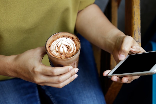 Zakończenie wizerunek kobieta lub samiec wręcza używać smartphone przy kawiarnią podczas gdy pijący kawę