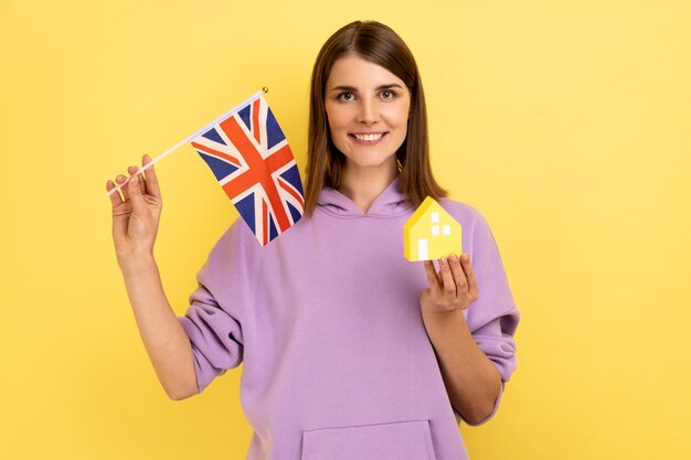 Zakup nieruchomości w Wielkiej Brytanii imigracja Kobieta trzymająca brytyjską flagę i papierowy dom
