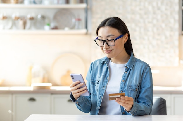 Zakupy online uśmiechnięta młoda piękna Azjatka składa zamówienie online i płaci za