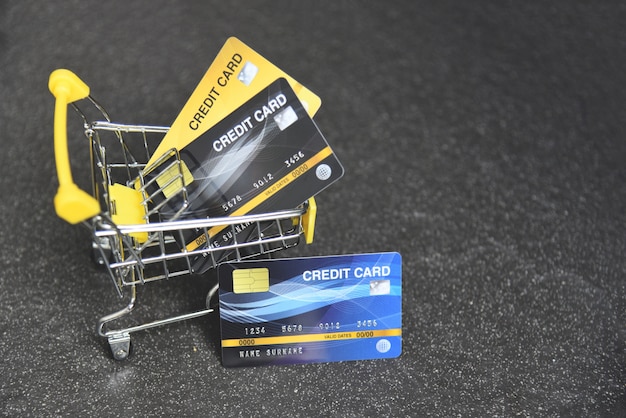 Zdjęcie zakupy online za pomocą karty kredytowej w koszyku na ciemnym tle do płatności online w domu