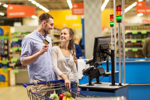 zakupy, sprzedaż, płatność, konsumpcjonizm i koncepcja ludzi - szczęśliwa para z kartą bankową kupująca żywność w sklepie spożywczym lub supermarkecie kasy samodzielnej