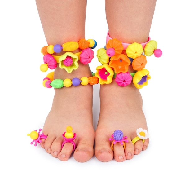 Załóż dziecku stopy kolorowe zabawki biżuteryjne koraliki dekoracje na białym tle Pojęcie szczęścia dzieci