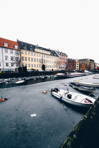 Zdjęcie zamarznięty kanał z budynkami i łodziami w kopenhaga