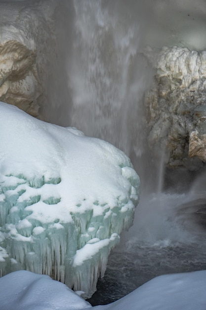 Zamarznięty wodospad Kvernufoss ze śniegiem i stalagmitami z opadającą wodą