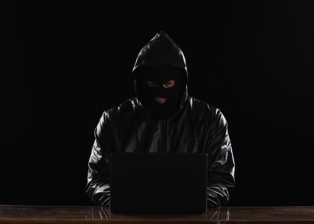 zamaskowany haker z laptopem