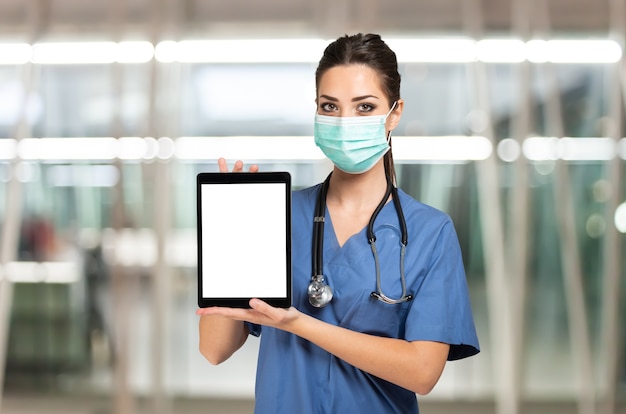 Zamaskowany lekarz pielęgniarka pokazujący tablet z białym ekranem