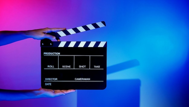 Zamazane Obrazy Planszy Filmowej Lub Tablicy Klapy. Ręka Trzyma Pusty Film Co Clapperboard Na Kolorowym Tle W Studio Do Filmowania Lub Nagrywania Filmów. Plansza Filmowa Do Produkcji Wideo Na Youtuber.