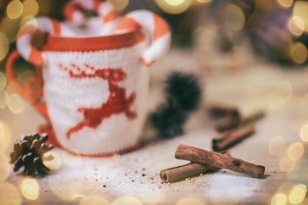 Zamazany obraz świątecznego kubka i laski cynamonu na drewnianym tle piękny efekt bokeh