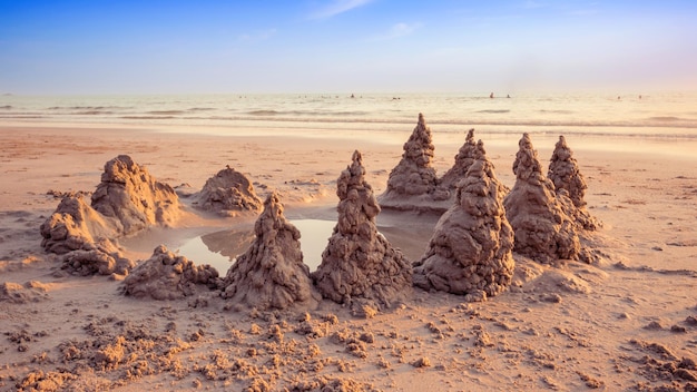 Zamek z piasku na plaży z rozgrzewającym światłem i pięknym niebem o zachodzie słońca w czasie letnich wakacji