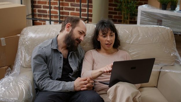 Zamężni właściciele domów szukający inspiracji do dekoracji domu, kupują meble na stronie zakupów online. Wspólna przeprowadzka do nowej nieruchomości, mieszkanie kupione na kredyt hipoteczny.