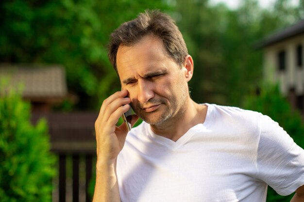 Zamknąć widok przekonany, przystojny mężczyzna rozmawia przez telefon komórkowy na zewnątrz. Biznesmen podejmowania rozmowy telefonicznej, dzwoniąc na smartfona. Kopiowanie przestrzeni, lato, komunikacja, ludzie, koncepcja cyfrowych gadżetów