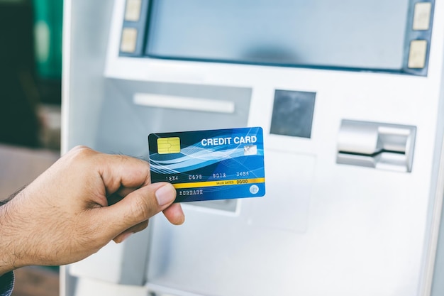 Zamknij męską rękę za pomocą kredytu Aby wypłacić pieniądze z bankomatu Man Machine włóż kartę bankomatową do automatu bankowego