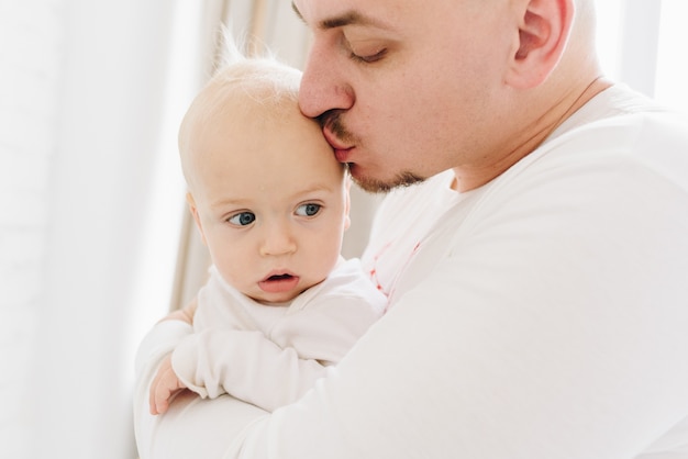 Zamknij się kochający kaukaski tata trzymając i całując swoje małe dziecko