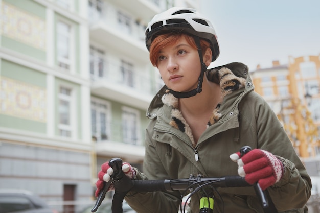 Zamknij się młoda kobieta w kasku rowerowym, jazda na rowerze po ulicach miasta