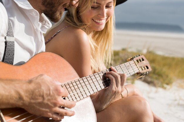 Zamknij się młody człowiek gra na gitarze akustycznej na plaży