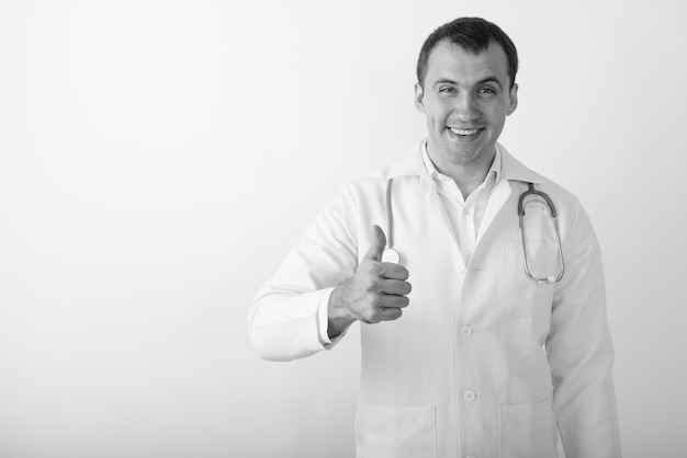 Zamknij się młody szczęśliwy muskularny mężczyzna lekarz uśmiechając się, dając kciuk do góry