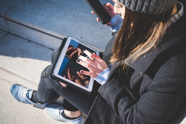 Zdjęcie zamknij się na rękach młodej kobiety dotykając ekranu tabletu