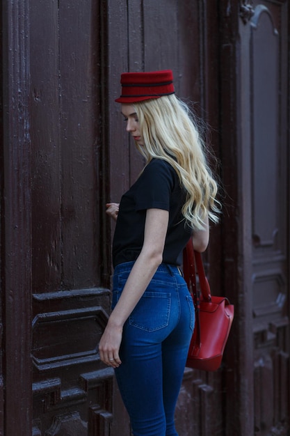 Zamknij się obraz modnej kobiety w mieście. Ubrana w niesamowitą modną czarną koszulę i czerwoną czapkę.