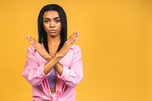Zamknij się portret poważnej młodej afroamerykańskiej kobiety pokazujący gest zatrzymania z dłonią odizolowaną na żółtym tle