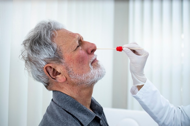 Zamknij się starszy mężczyzna robi badanie nosa PCR w biurze lekarzy podczas epidemii wirusa koronowego