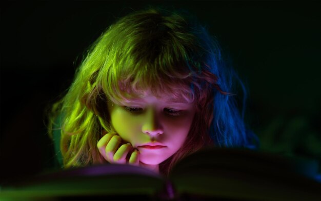 Zamknij się twarz dziecka czytającego magiczną książkę w łóżku chłopiec dziecko czyta książki w domu
