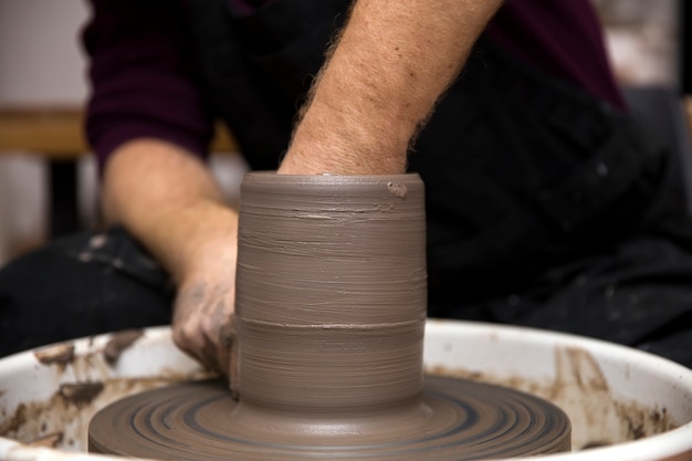 Zamknij się widok szczegółów na artystę sprawia, że ​​ceramika gliny na kole wirowania
