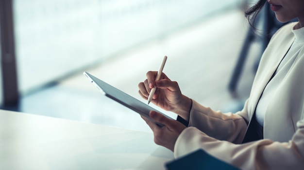 Zamknij się z businesswoman trzymając pióro, pracując na tablecie w biurze.