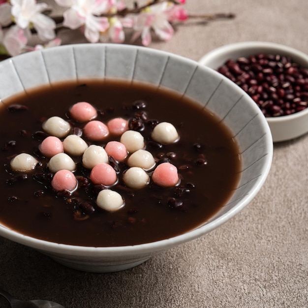 Zamknij się z czerwonego i białego tangyuan (tang yuan, kleisty ryż kluski kulki) ze słodką zupą z czerwonej fasoli w misce na szarym tle tabeli na festiwal przesilenia zimowego.