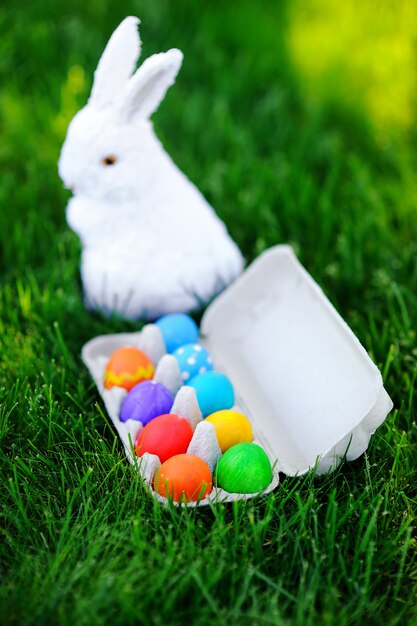Zamknij się zdjęcie kolorowe pisanki i biały króliczek na zielonej trawie na zewnątrz