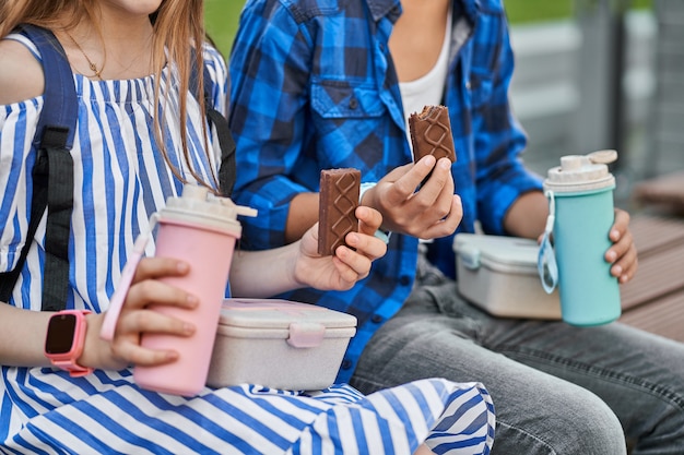 Zdjęcie zamknij się zdjęcie obiadu dzieci z różowym lunchbox i niebieskim termosem i ciastem.