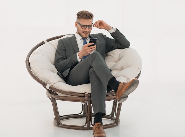 Zamknij udanego biznesmena czytającego SMS-a na swoim smartfonie na białym tle