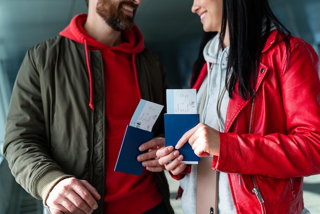 Zamknij widok pary podróżującej patrząc na siebie, niosąc paszport i bilety podczas stania w hali lotniska przed podróżą. Zdjęcie stockowe