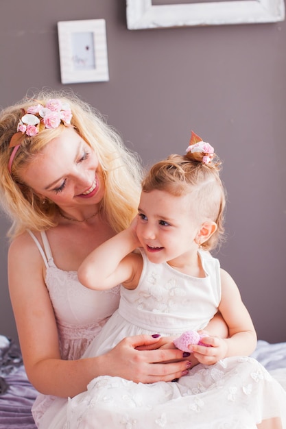 Zamknij widok portret pięknej blondynki matki i córki w białej sukni w ich stylowej sypialni