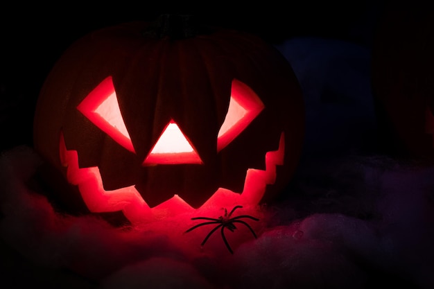 Zamknij widok przerażającej dyni Halloween z oczami świecącymi w środku na czarnym tle