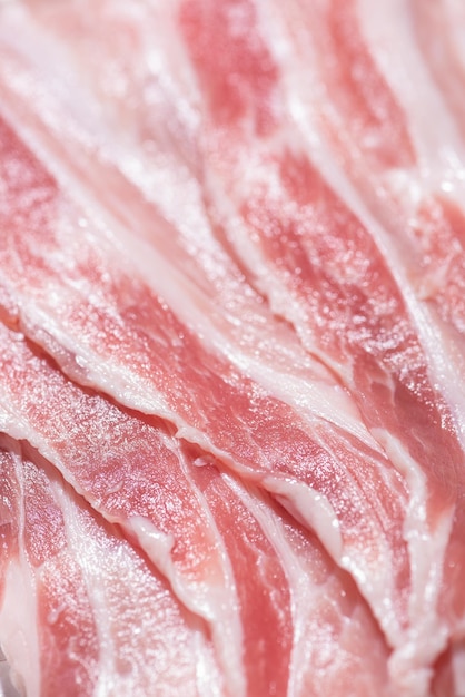 Zamknij widok z góry paczka kawałki bekonu surowe mięso świeżej czerwonej wieprzowiny z plastrami białego tłuszczu są krojone w cienkie paski ułożone jeden na drugim