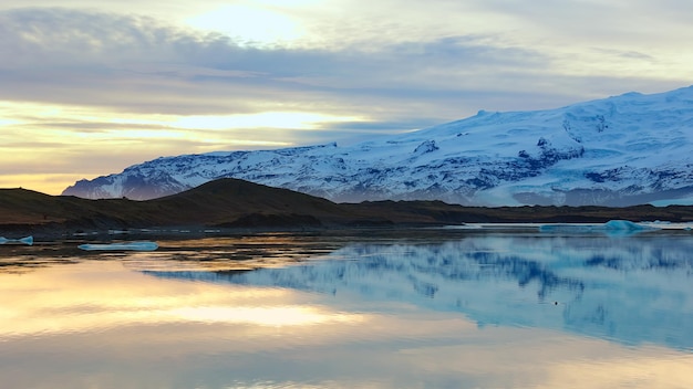 Zamrożone jezioro z górami i spektakularnym śnieżnym krajobrazem, zamarzająca zimna woda. Piękna naturalna krajobraz z otwartymi polami i skandynawską trasą malowniczą, Islandia.