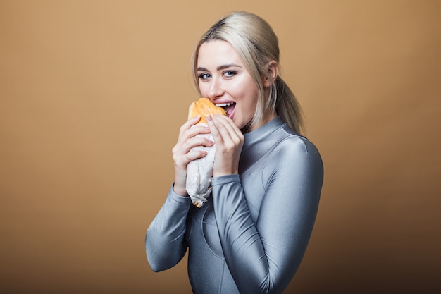 Zamyka Up Głodna Kobieta Z Otwartym Usta, Trzymający Dużą Kanapkę I Jedzący. Pojęcie Fast Food
