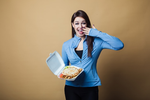 Zamyka Up Głodna Kobieta Z Otwartym Usta, Trzymający Dużą Kanapkę I Jedzący. Pojęcie Fast Food