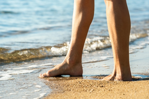 Zamyka up kobieta cieki chodzi boso na piasku opuszcza odciski stopy na złotej plaży