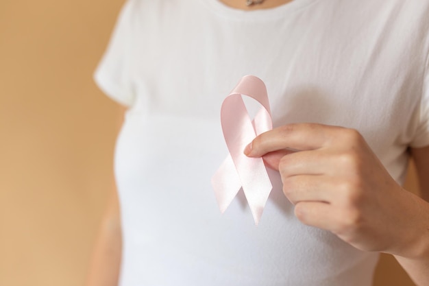 Zamyka up kobieta seansu różowy faborek symbolizuje raka piersi