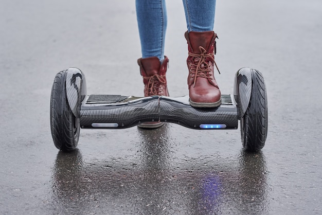 Zamyka up kobieta używa hoverboard na asfaltowej drodze. Stopy na skuterze elektrycznym na zewnątrz