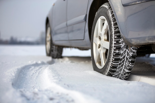 Zamyka up samochodowa opona parkująca na śnieżnej drodze na zima dniu. Koncepcja transportu i bezpieczeństwa.