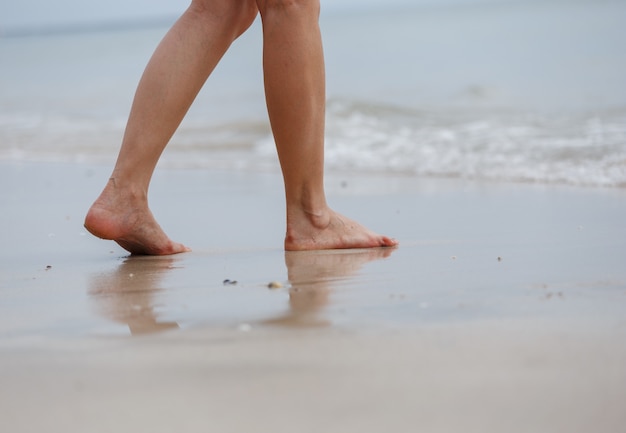 Zamyka up żeńskie nogi chodzi na plaży