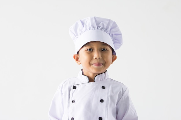 Zamyka w górę azjatykciej chłopiec jest ubranym szefa kuchni mundur