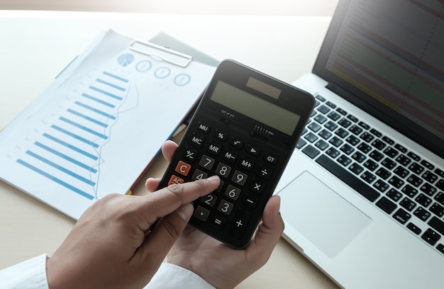 Zamyka w górę biznesmena używa kalkulatora na finansowym use kalkuluje o koszcie przy biurem