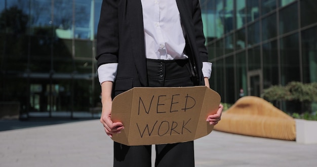 Zdjęcie zamyka w górę bizneswomanu mienia afiszowego kartonu z potrzebą pracy bezrobotnym komunikatem globalne bezrobocie