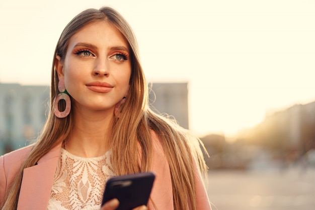 Zamyka w górę portreta młoda kobieta opowiada na jej telefonie na ulicie