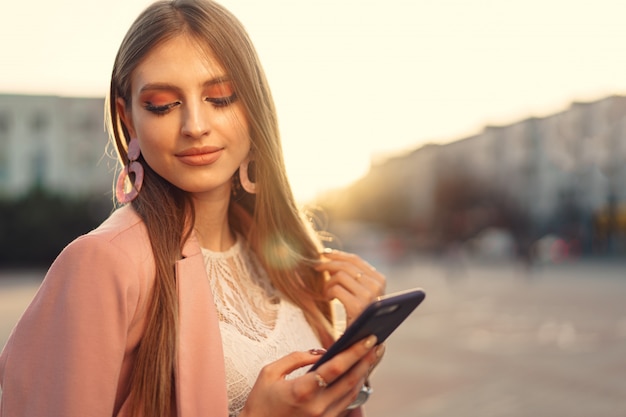 Zamyka w górę portreta młoda kobieta opowiada na jej telefonie na ulicie